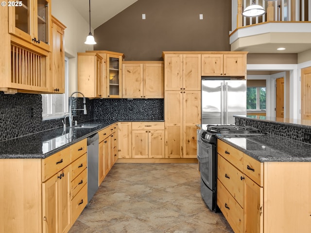 kitchen with dark stone counters, light brown cabinetry, appliances with stainless steel finishes, and glass insert cabinets