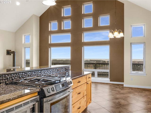 kitchen with a chandelier, high vaulted ceiling, light brown cabinets, baseboards, and appliances with stainless steel finishes