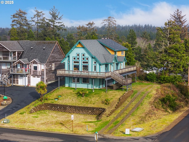 exterior space featuring driveway, stairway, a lawn, and a wooden deck