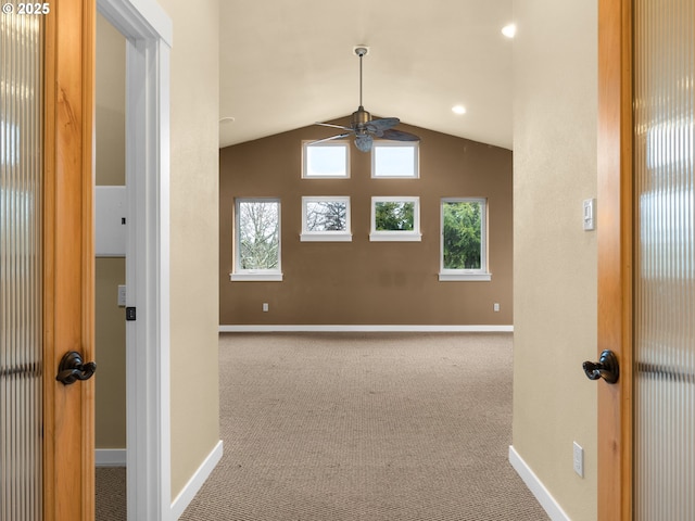 unfurnished room featuring light carpet, vaulted ceiling, a ceiling fan, and baseboards