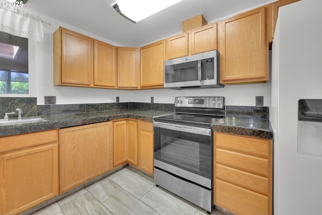 kitchen featuring a sink, light brown cabinets, dark countertops, and appliances with stainless steel finishes