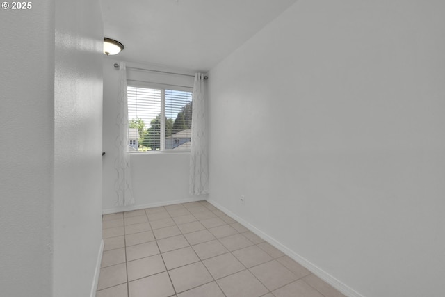 empty room with baseboards and light tile patterned floors
