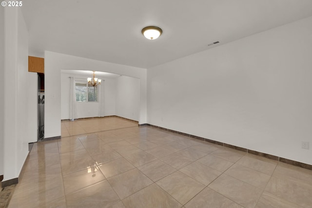 spare room with light tile patterned flooring, a notable chandelier, and baseboards