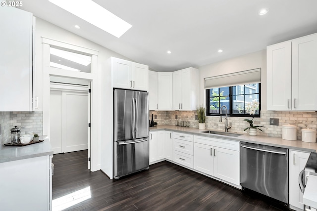 kitchen with stainless steel appliances, a sink, decorative backsplash, dark wood finished floors, and light countertops