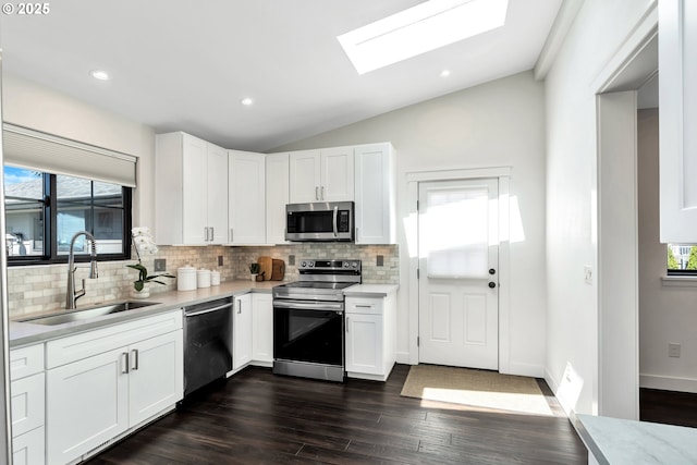 kitchen with a sink, stainless steel appliances, a skylight, light countertops, and tasteful backsplash