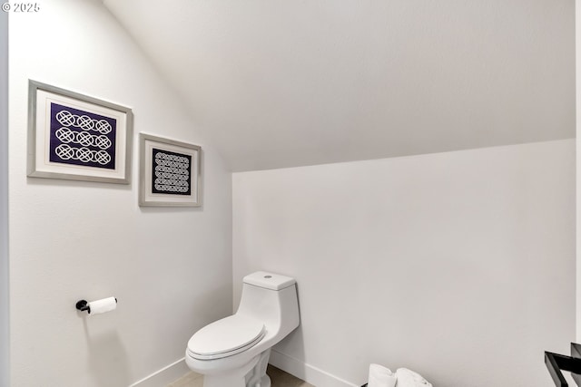 bathroom featuring baseboards, vaulted ceiling, and toilet