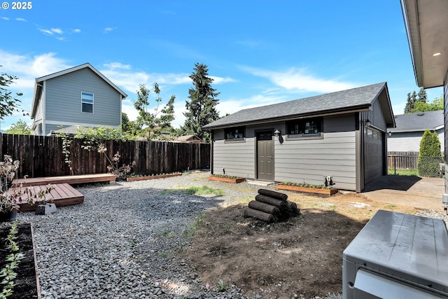fenced backyard featuring an outdoor structure, a garage, and a deck