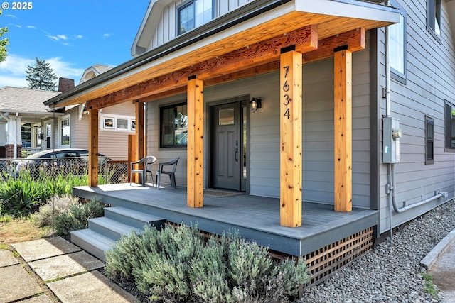 doorway to property featuring a porch and fence