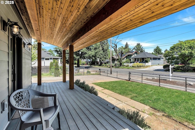 wooden terrace featuring covered porch, a residential view, and fence
