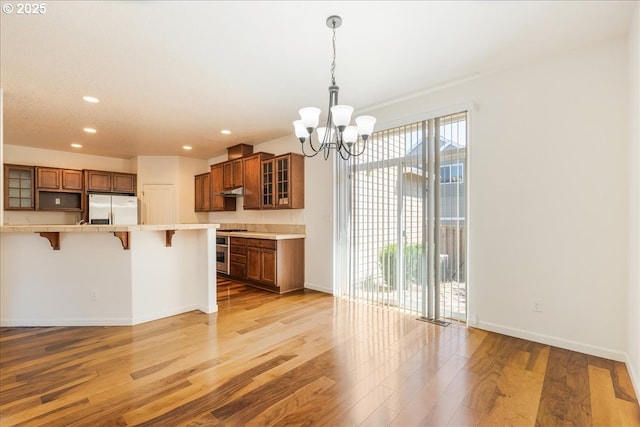 5944 SE Thornapple St, Hillsboro, OR 97123 - kitchen with stainless steel fridge, a breakfast bar, brown cabinets, a chandelier, and light wood-style flooring