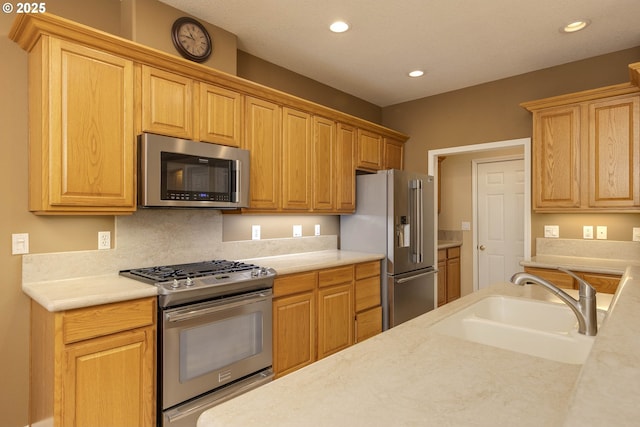 kitchen with appliances with stainless steel finishes, light countertops, a sink, and recessed lighting