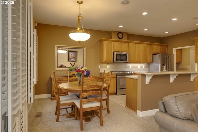 kitchen with a breakfast bar, a peninsula, stainless steel appliances, light countertops, and recessed lighting