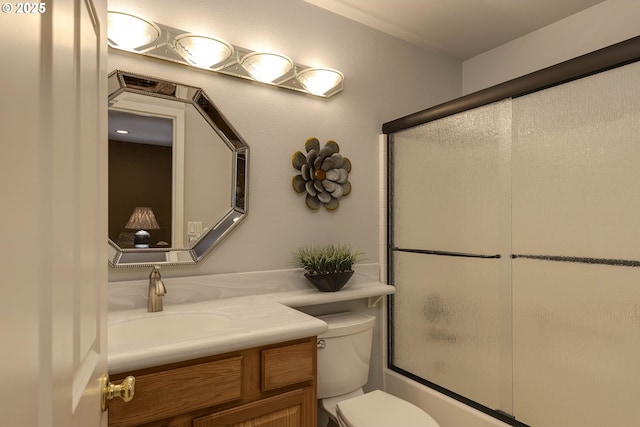 bathroom with enclosed tub / shower combo, vanity, and toilet