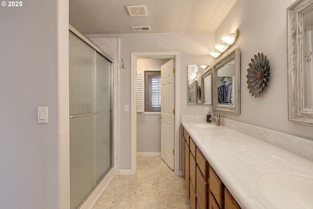 bathroom with double vanity, a stall shower, visible vents, and a sink