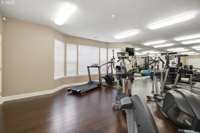 workout area with a textured ceiling, baseboards, and wood finished floors