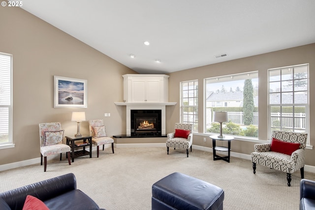 sitting room with vaulted ceiling, carpet, a glass covered fireplace, and plenty of natural light