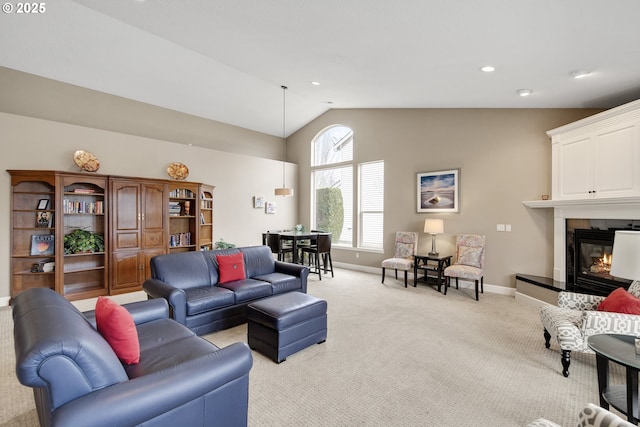 living room featuring lofted ceiling, recessed lighting, light colored carpet, a glass covered fireplace, and baseboards