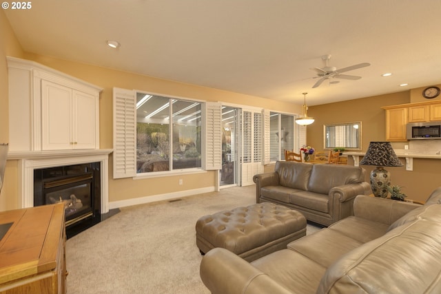 living room with recessed lighting, light colored carpet, a fireplace with flush hearth, a ceiling fan, and baseboards