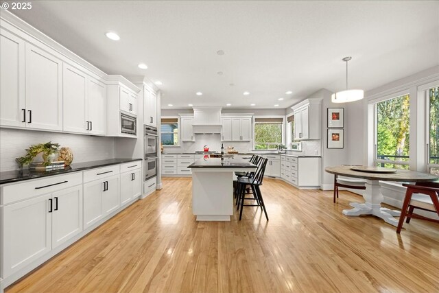 9522 NW Skyview Dr, Portland, OR 97231 - kitchen with dark countertops, decorative backsplash, a breakfast bar area, recessed lighting, and white cabinetry