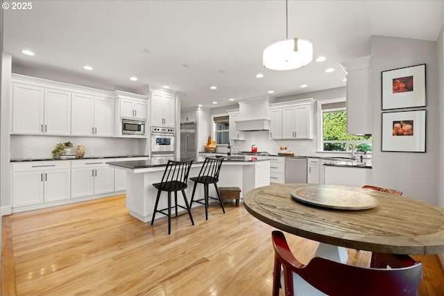 9522 NW Skyview Dr, Portland, OR 97231 - kitchen with built in appliances, premium range hood, a sink, white cabinets, and recessed lighting