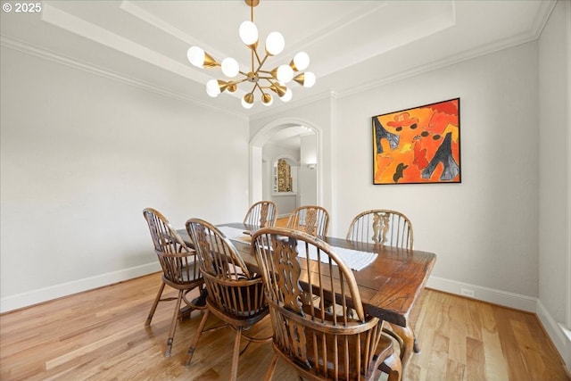 9522 NW Skyview Dr, Portland, OR 97231 - dining area with arched walkways, a raised ceiling, a chandelier, light wood finished floors, and baseboards