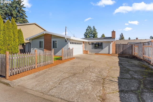 ranch-style home featuring a garage, fence private yard, concrete driveway, and a chimney