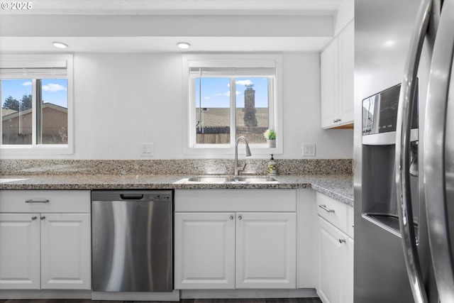 kitchen with recessed lighting, stainless steel appliances, a sink, white cabinetry, and light stone countertops