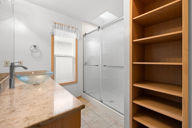 bathroom with sink, a skylight, and a shower with door