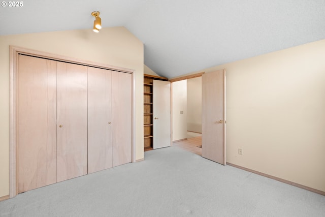 unfurnished bedroom with a closet, light colored carpet, and lofted ceiling