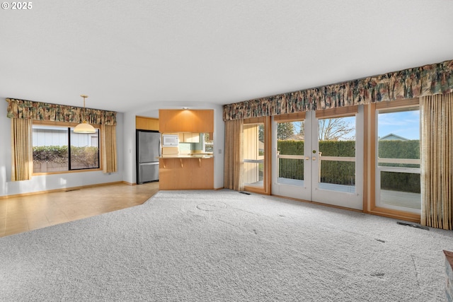 unfurnished living room with light colored carpet and french doors