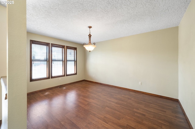 empty room featuring wood finished floors, a textured ceiling, and baseboards