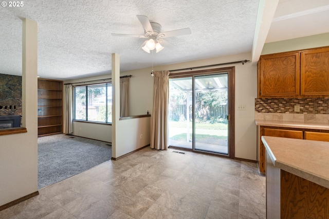 interior space featuring baseboards, a ceiling fan, a textured ceiling, and visible vents