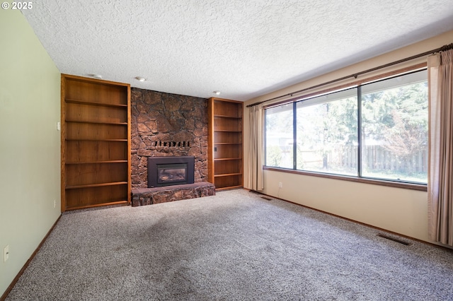 unfurnished living room with a fireplace, a textured ceiling, and a wealth of natural light