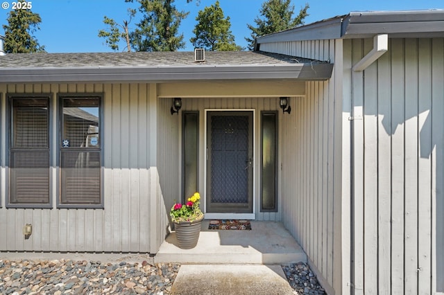 doorway to property with a porch and roof with shingles