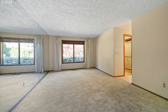 carpeted empty room with baseboards and a textured ceiling