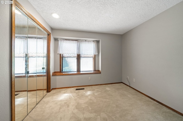 carpeted empty room with baseboards, visible vents, and a textured ceiling