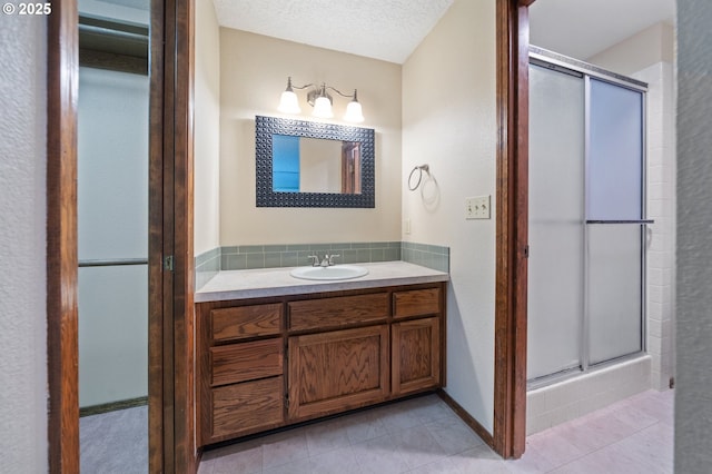 full bath featuring a shower stall, vanity, tile patterned floors, and a textured ceiling