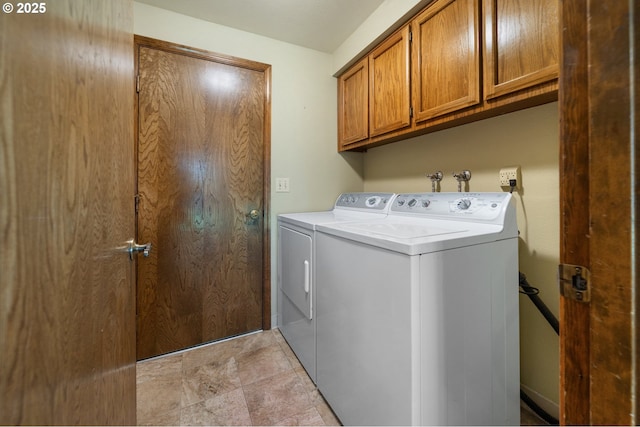 clothes washing area featuring cabinet space, stone finish floor, and washing machine and clothes dryer