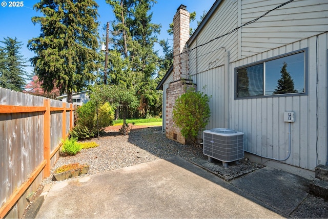 view of property exterior featuring central AC unit, a chimney, fence, board and batten siding, and a patio