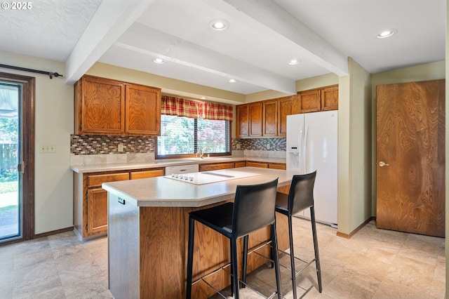 kitchen with backsplash, light countertops, white appliances, and brown cabinets