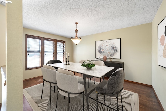 dining area with wood finished floors, a textured ceiling, and baseboards