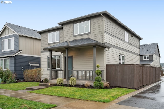 view of front of home with a porch, a front yard, and fence