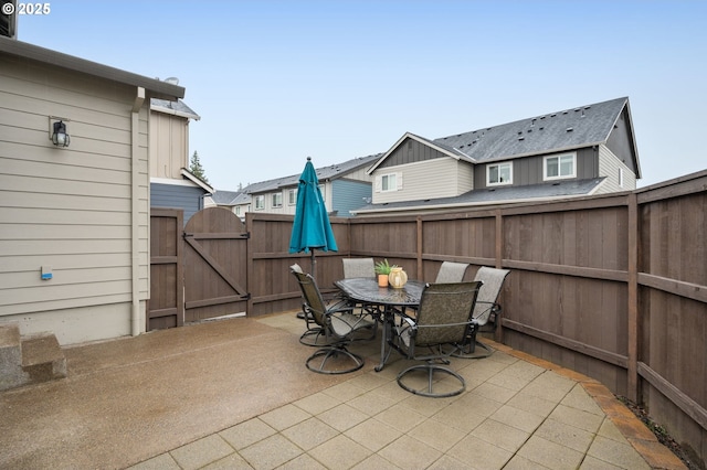 view of patio / terrace featuring fence, outdoor dining space, and a gate