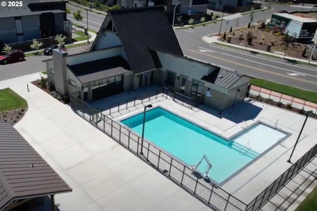 community pool with a patio area and fence