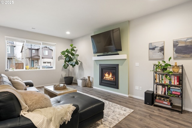 living room with a glass covered fireplace, recessed lighting, wood finished floors, and baseboards