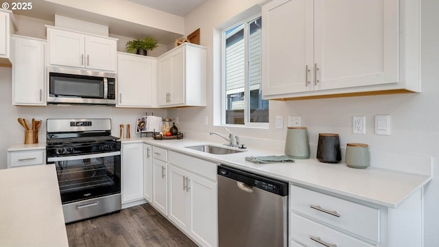 kitchen with stainless steel appliances, a sink, light countertops, and white cabinets