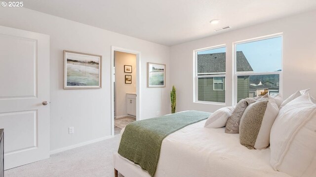bedroom featuring light carpet, baseboards, and ensuite bath