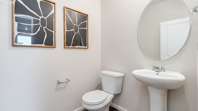 bathroom featuring toilet, a sink, and baseboards