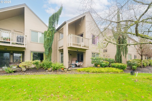 rear view of property with a yard and a balcony