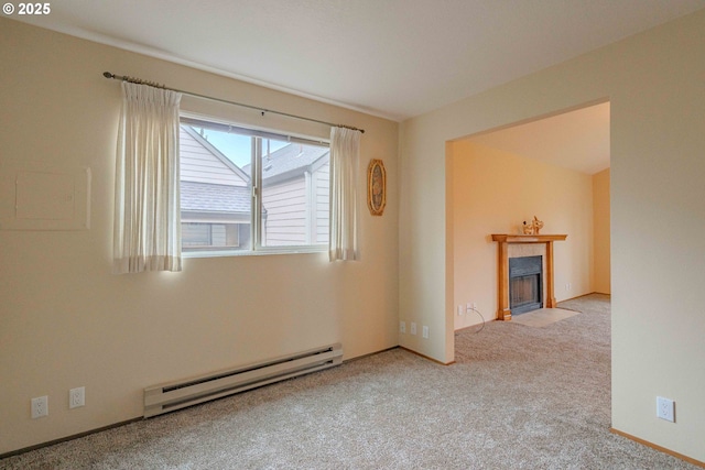 empty room featuring a tile fireplace, baseboards, a baseboard heating unit, and carpet